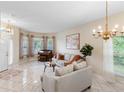 Bright living room with natural light, neutral-toned furniture, and tile flooring with a decorative chandelier overhead at 5509 Florence Harbor Dr, Orlando, FL 32829