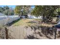 Fenced backyard featuring a grassy lawn, mature trees, and space for parking or other recreational activities at 9350 2Nd Ave, Orlando, FL 32824