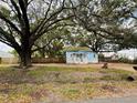 Quaint blue house with white trim, complemented by mature trees, a small front porch, and a fenced yard at 9350 2Nd Ave, Orlando, FL 32824
