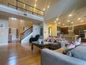 Open-concept living room with hardwood floors, comfortable seating, open staircase, and easy access to kitchen at 9526 Lake Hugh Dr, Gotha, FL 34734