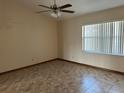 A bright bedroom featuring tiled floor, ceiling fan and a window with vertical blinds at 1811 Springwood Ln, Deltona, FL 32725