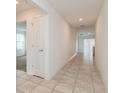 Hallway featuring neutral tile flooring, recessed lighting, and white doors with a view into a living room at 1950 Birnham Wood Bnd, Kissimmee, FL 34746