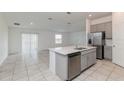 Bright open-concept kitchen featuring stainless steel appliances, grey cabinets, and a large island with a sink at 1950 Birnham Wood Bnd, Kissimmee, FL 34746