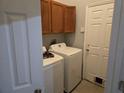 Functional laundry room featuring appliances, wooden cabinets, and tiled flooring at 2119 Kaylas Ct, Orlando, FL 32817