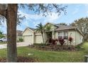 Landscaped home with a spacious three-car garage, vibrant flowerbeds, and brick driveway at 3289 Saloman Ln, Clermont, FL 34711