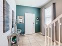 Inviting foyer with tiled flooring, a decorative console table, and a stairway leading to the upper level at 3401 Lilac Way, Davenport, FL 33897