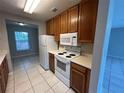 Well-lit kitchen with white appliances, wood cabinetry, tile floors, and access to an adjacent room at 4013 Dijon Dr # 4013K, Orlando, FL 32808