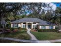 Stunning single-story home with brick walkway, lush landscaping, and blue shutters, framed by mature trees and a blue sky at 4978 Fawn Ridge Pl, Sanford, FL 32771