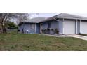 View of blue home featuring a single car garage and low maintenance lawn at 5843 Willow Leaf Ct, Orlando, FL 32807