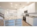 Modern kitchen featuring white cabinets, granite countertops, stainless steel appliances, and an island at 6627 Lullaby Way, Mascotte, FL 34753