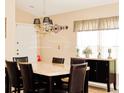 Dining room with modern chandelier, granite-topped table, dark wood accents, and natural light at 109 Grosvenor Loop, Davenport, FL 33897