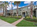 Beautiful townhome with a well-manicured lawn, brick walkway, and vibrant landscaping with mature palm trees at 14849 Driftwater Dr, Winter Garden, FL 34787