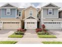 Inviting townhome showcasing colorful landscaping, neutral siding, brick paver walkway, and attached one car garage at 2258 Sedge Grass Way, Orlando, FL 32824