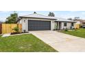 Charming single-story home with a gray metal roof, a well-manicured lawn, and a dark gray garage door at 2335 Montano St, Deltona, FL 32738