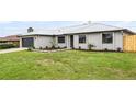 A well-manicured lawn frames a charming single-story home with a gray metal roof and a dark gray garage door at 2335 Montano St, Deltona, FL 32738