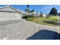View of the exterior of a single Gathering home with paved driveway and manicured lawn and landscaping at 2628 Caribe Dr, The Villages, FL 32162