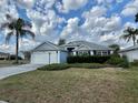 Inviting one-story home featuring a two car garage, well trimmed bushes, and a palm tree at 2628 Caribe Dr, The Villages, FL 32162