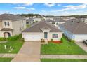 Aerial view of a well-maintained one-story home with a manicured lawn, two-car garage, and a welcoming entrance at 3871 Brant Pl, Leesburg, FL 34748