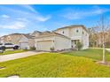 Two-story home featuring a two-car garage, brick driveway, well-manicured lawn, and neutral-colored exterior at 5237 Royal Point Ave, Kissimmee, FL 34746