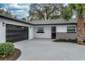 Charming single-story home showcasing a well-manicured lawn, a dark two-car garage door, and a welcoming front entrance at 605 Hill Ave, Ocoee, FL 34761