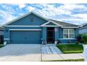 Inviting blue single-story home with a two-car garage and neatly landscaped front yard at 756 Kindred Ln, Auburndale, FL 33823