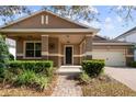 Charming home exterior featuring a cozy front porch, brick driveway, and landscaped garden at 11619 Chateaubriand Ave, Orlando, FL 32836