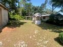 Spacious backyard with a small wooden deck, decorative wishing well, and mature trees at 12314 Virginia Dr, Leesburg, FL 34788