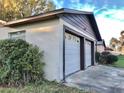 Side view of an attached two-car garage with white doors and brown trim, surrounded by greenery at 12314 Virginia Dr, Leesburg, FL 34788