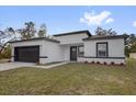 Single-story home with a two-car garage, dark trim, modern design elements, and fresh landscaping in a bright setting at 13817 Sw 43Rd Cir, Ocala, FL 34473