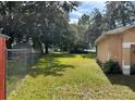 View of the grassy, fenced backyard with mature trees, offering privacy and space at 231 Cranbrook Dr, Kissimmee, FL 34758