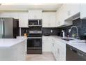 Well-lit kitchen featuring white cabinets, stainless appliances, and sleek gray subway tile backsplash at 3121 Paradox Cir # 203, Kissimmee, FL 34746