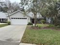 Street view of single-story home with a two-car garage and mature landscaping at 3315 Newbliss Cir, Ormond Beach, FL 32174