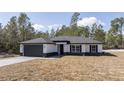 Charming single-story home with gray driveway, dark gray garage door and black shutters at 41915 Aspen St, Eustis, FL 32736