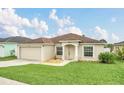 Well-maintained single-story home featuring a two-car garage and lush green lawn at 445 Peter Pan Blvd, Davenport, FL 33837