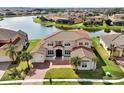 Aerial view of a beautiful stucco home with a red roof, well-manicured lawn and lake views at 890 Spinnaker Way, Kissimmee, FL 34746