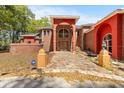 Inviting brick home showcasing a grand stone pathway, archway entrance, and lush surroundings at 19715 Eaglesview Cir, Umatilla, FL 32784