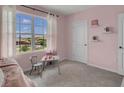 Cozy pink bedroom featuring a large window with scenic views, a comfortable bed, and stylish decor at 2972 Moulin Rd, Davenport, FL 33837