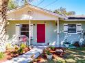 Close up of the inviting red front door flanked by colorful plants and an elegant white bench at 32804 Blossom Ln, Leesburg, FL 34788