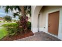 Close-up of the front door, framed by an arched entryway, brick walkway, and vibrant landscaping at 3854 Carrick Bend Dr, Kissimmee, FL 34746