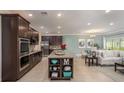 Spacious kitchen boasts dark wood cabinets, granite countertops, and stainless steel appliances, open to living area at 6598 Lullaby Way, Mascotte, FL 34753
