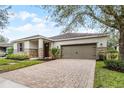 Charming home featuring a stone facade, tan siding, a two car garage, and a brick paver driveway at 8807 Tatara St, Orlando, FL 32836