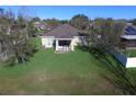 Aerial view of a home's backyard with a lush green lawn, a covered patio, and mature trees, perfect for outdoor living at 1107 Galway Blvd, Apopka, FL 32703