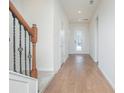 Bright hallway features wood-look tile floors, access to the front door and a staircase with rod iron details at 14250 Lanikai Beach Dr, Orlando, FL 32827