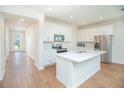 Modern white kitchen features stainless steel appliances, center island with sink, and beautiful floors at 14250 Lanikai Beach Dr, Orlando, FL 32827