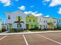 Street view showcasing colorful townhomes with parking spaces, trees, and vibrant architectural details at 2927 Castaway Ln, Kissimmee, FL 34747