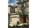 Two-story home featuring neutral stucco, tan garage door, well-maintained landscaping, and a shade tree at 3587 Davenport Creek Ct, Kissimmee, FL 34746