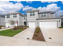 Attractive gray townhomes featuring attached garages and tidy landscaping on a sunny, bright day at 4653 Sparkling Shell Ave, Kissimmee, FL 34746