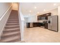 Modern, open-concept kitchen with stainless steel appliances and dark wood cabinets adjacent to carpeted stairs at 4653 Sparkling Shell Ave, Kissimmee, FL 34746