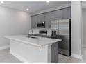 Kitchen with gray cabinets, stainless steel appliances, and a spacious island with countertop at 7838 Spectrum Dr, Kissimmee, FL 34747