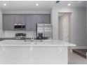 Well-lit kitchen with gray cabinets, stainless steel appliances, and countertop island with sink at 7838 Spectrum Dr, Kissimmee, FL 34747